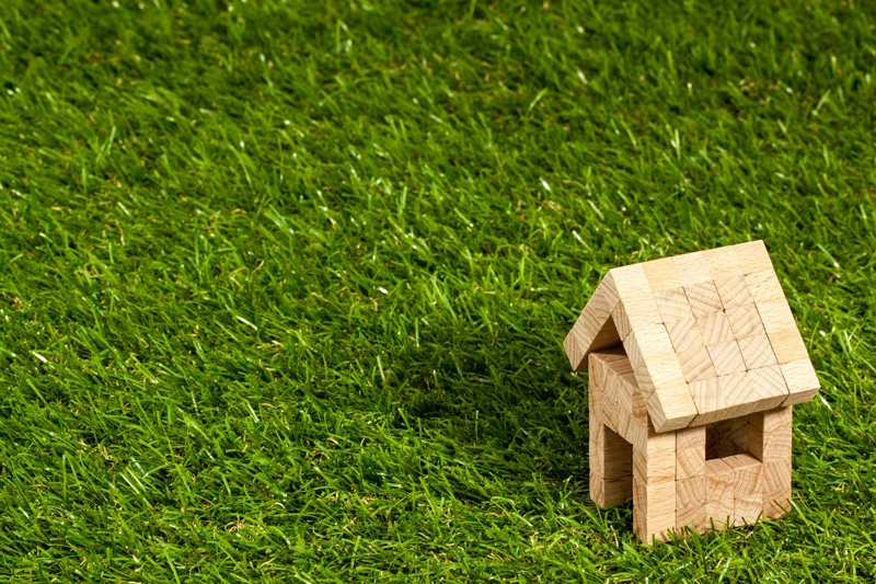 A house made of wooden blocks on some grass